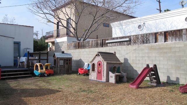 Outdoor area with slide, toy car, table, chairs.